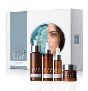 A skincare trial set by Esse for sensitive skin, featuring four brown bottles and jars of different sizes in front of a white and blue box with a circular cutout showing part of a woman’s face and a blue flower.