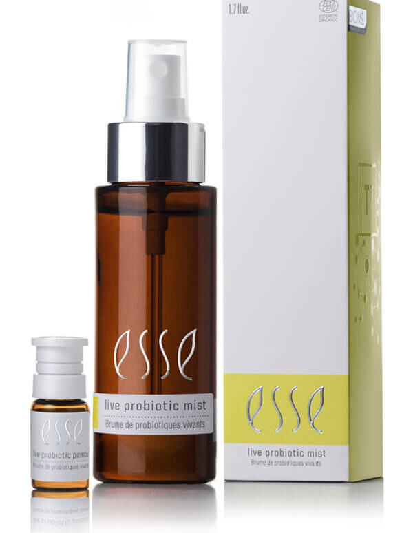 A 1.7 fl oz brown bottle labeled "Esse Live Probiotic Mist" stands beside a small vial and a tall white-and-yellow box, all featuring matching Esse branding.