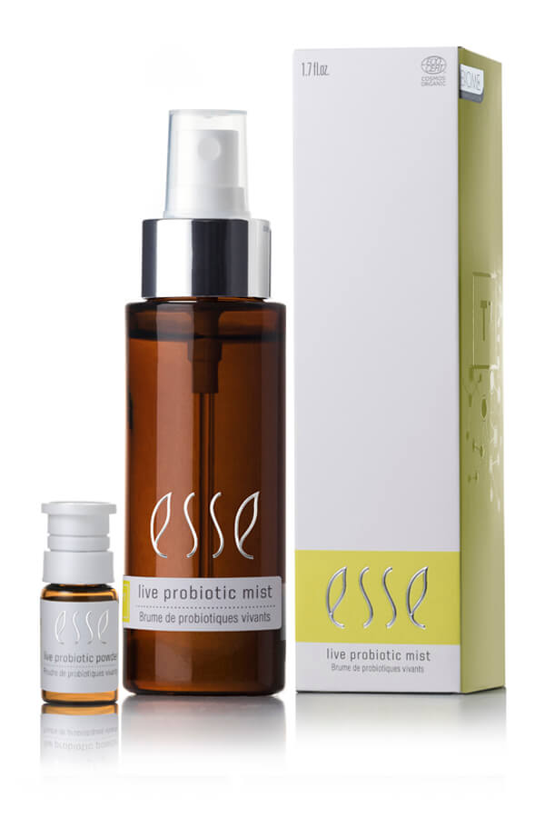 A 1.7 fl oz brown bottle labeled "Esse Live Probiotic Mist" stands beside a small vial and a tall white-and-yellow box, all featuring matching Esse branding.